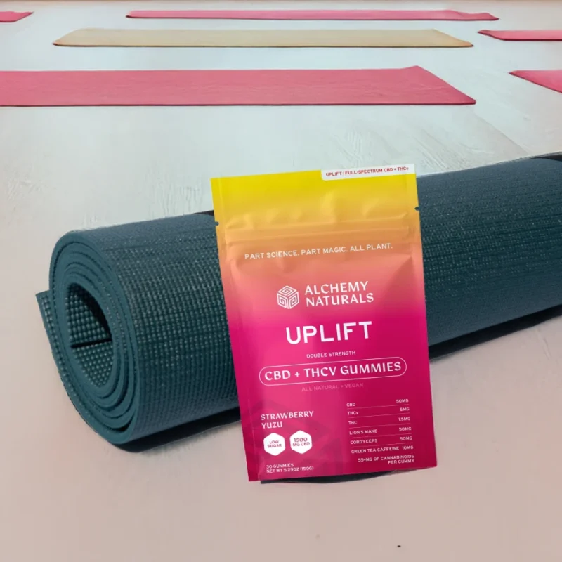 Alchemy Naturals Uplift CBD Gummies - Gummy Bag Leaning Against Yoga Mat on Floor
